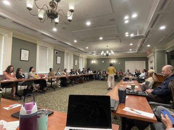 Researchers in a circle listening to Dr. Huang.